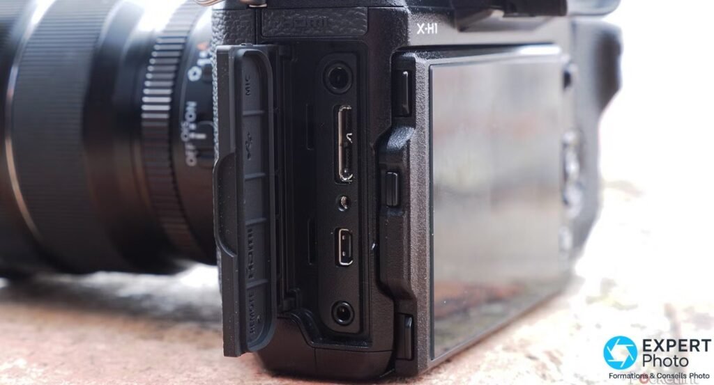Flanc gauche du Fujifilm X-H1 avec trappes de connectique ouvertes : ports micro, HDMI, USB et télécommande visibles. 