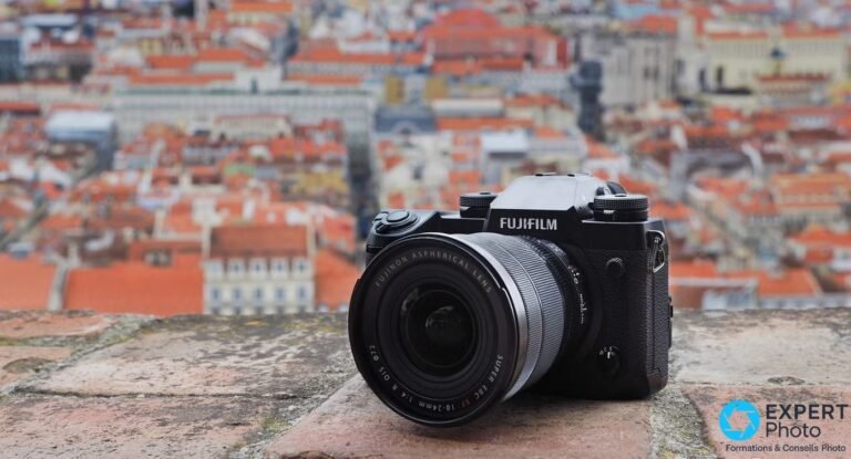 Boîtier hybride Fujifilm X-H1 noir équipé d'un objectif Fujinon XF 10-24mm f/4 OIS, posé sur un muret de pierre.