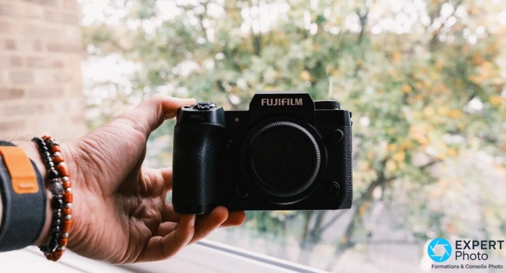 Boîtier Fujifilm X-H2 vu de face avec body cap noir Fujifilm monté, logo FUJIFILM visible en haut.