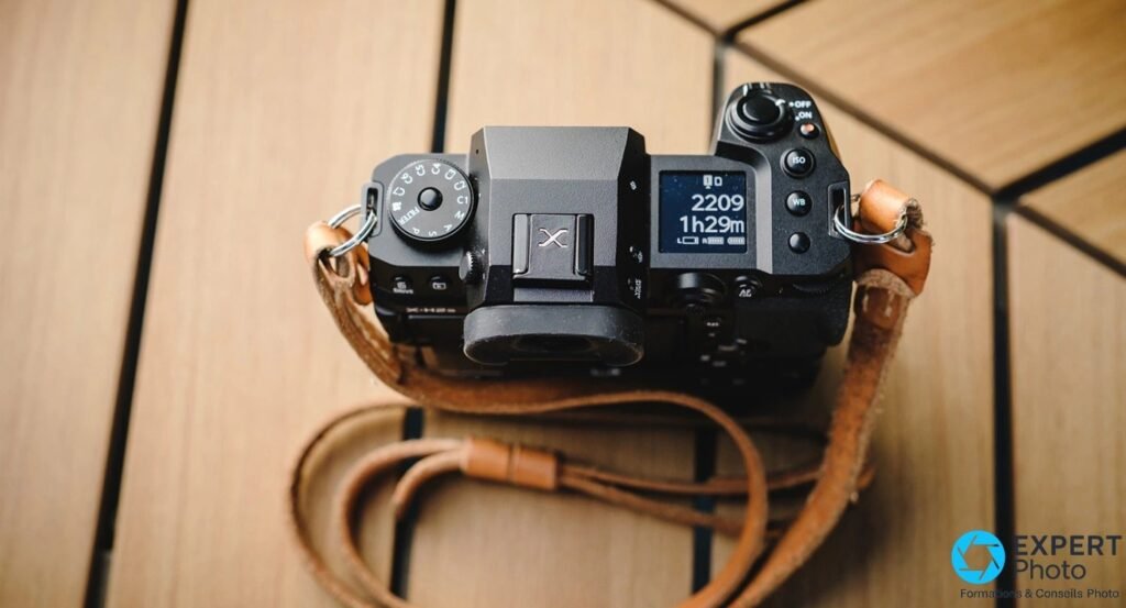 Fujifilm X-H2S vu de dessus, sangle cuir havane enroulée, logo X sur cache griffe, parquet bois clair