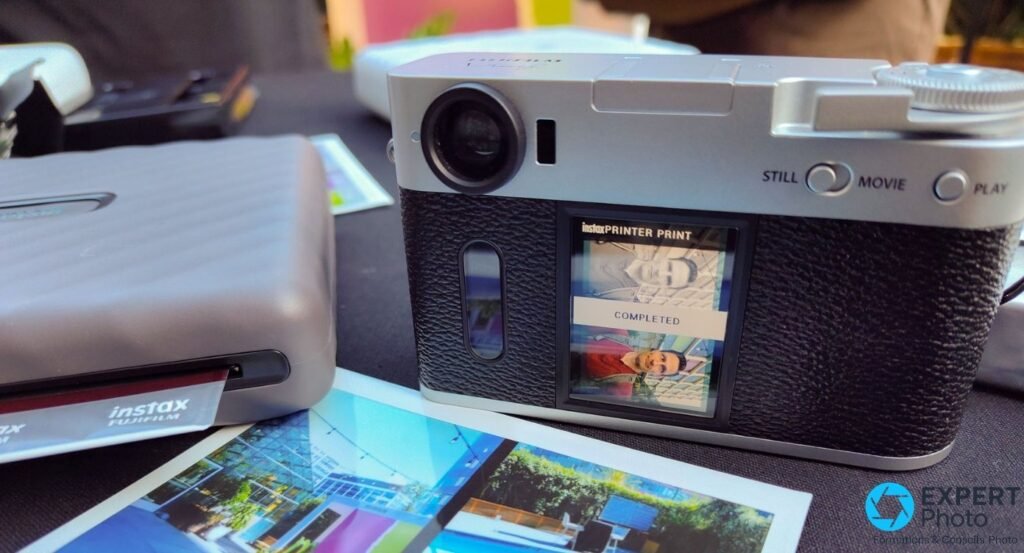 Fujifilm X Half vu de dos, écran arrière affichant 'instax PRINTER PRINT COMPLETED' avec imprimante instax à gauche.