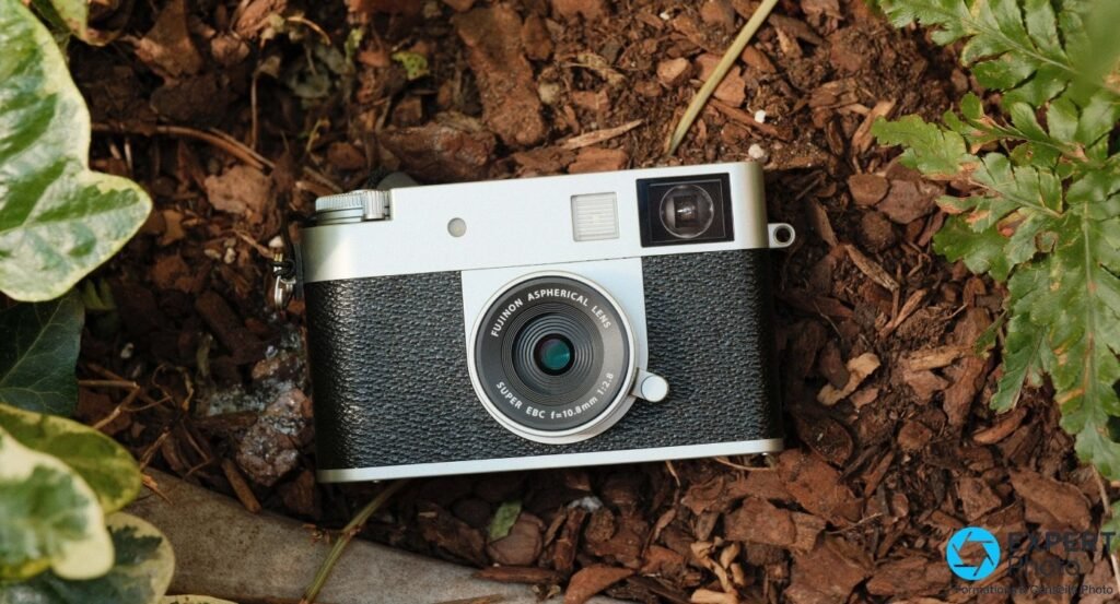 Fujifilm X Half argenté vu de face en plongée sur paillage d'écorce, feuilles de lierre et fougère sur les côtés.
