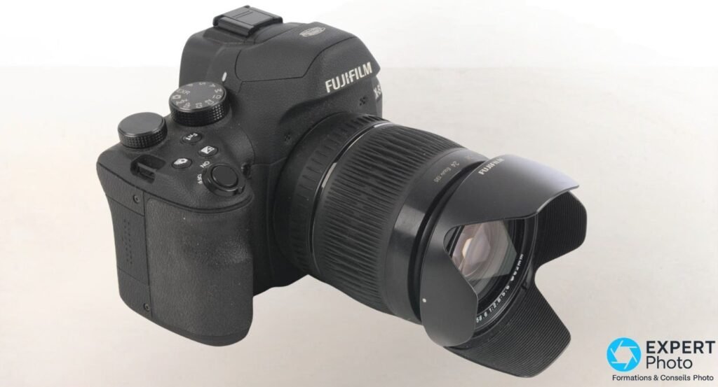  Fujifilm X-S1 de profil, zoom Fujinon 24-624 mm avec pare-soleil monté, marquage FUJIFILM et molette mode visibles.