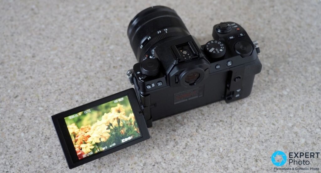Fujifilm X-S10 vu de trois quarts arrière, écran tactile orientable déplié vers l'avant, objectif XF 18-55 mm.