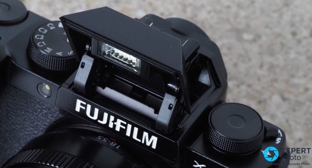 Flash intégré pop-up du Fujifilm X-S10 déployé en position haute, logo FUJIFILM visible avec objectif 18-55 mm.