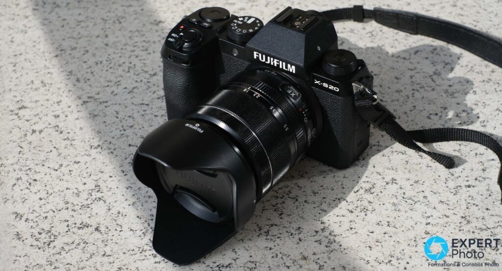 Fujifilm X-S20 avec XF 18-55mm, pare-soleil et bouchon Fujifilm, vu en plongée sur surface granit