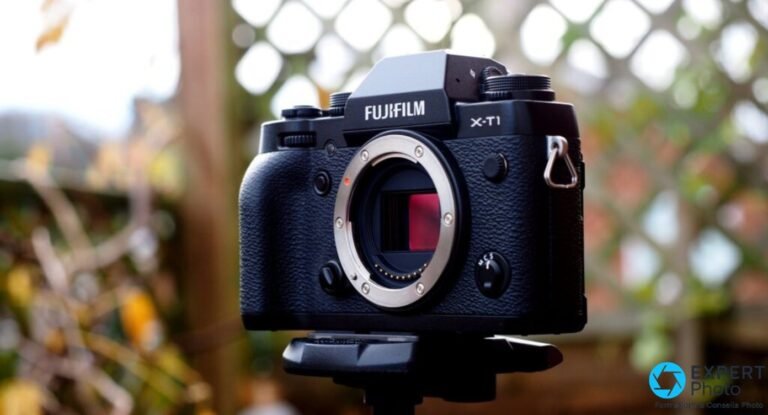 Test Fujifilm X-T1 : que vaut cet hybride APS-C en occasion Fujifilm X-T1 en vue de face avec objectif Fujinon XF 35mm f/2 R WR monte, pose sur un trepied, fond treillage flou