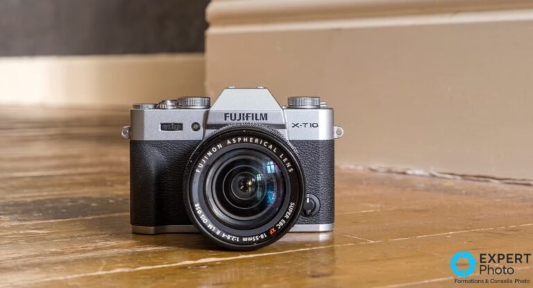 Fujifilm X-T10 silver vu de face avec objectif Fujinon XF 18-55mm f/2.8-4 OIS sur un plancher en bois.