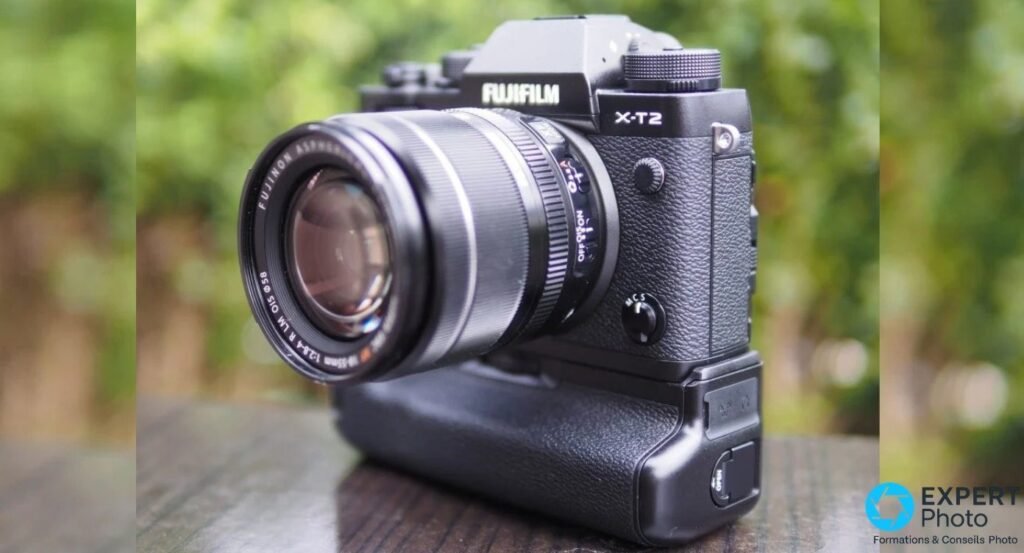 Fujifilm X-T2 monté avec le grip vertical VPB-XT2 et l'objectif XF 18-55mm, sur fond de végétation en bokeh.
