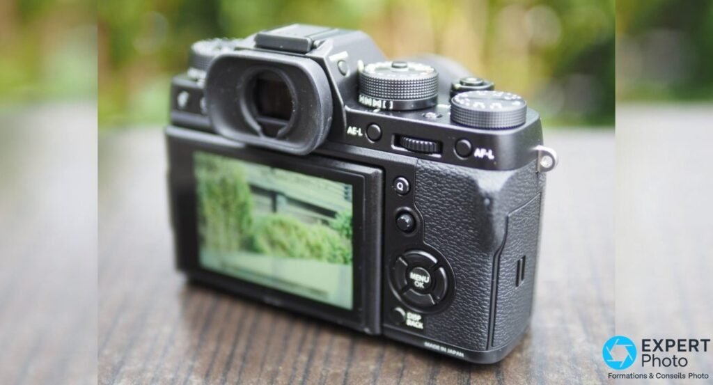 Vue arrière du Fujifilm X-T2 montrant l'écran rabattu, le viseur OLED, les molettes et les boutons AE-L et AF-L.