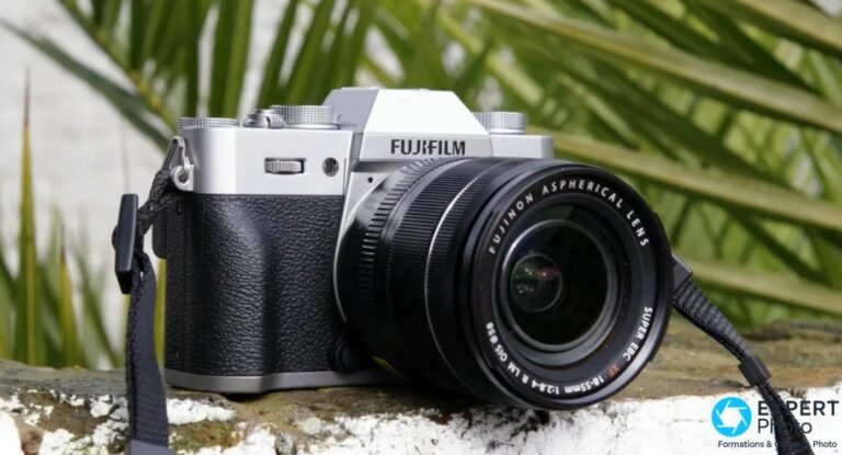 Fujifilm X-T20 argenté avec objectif XF 18-55mm posé sur muret pierre, vue trois quarts avant en extérieur
