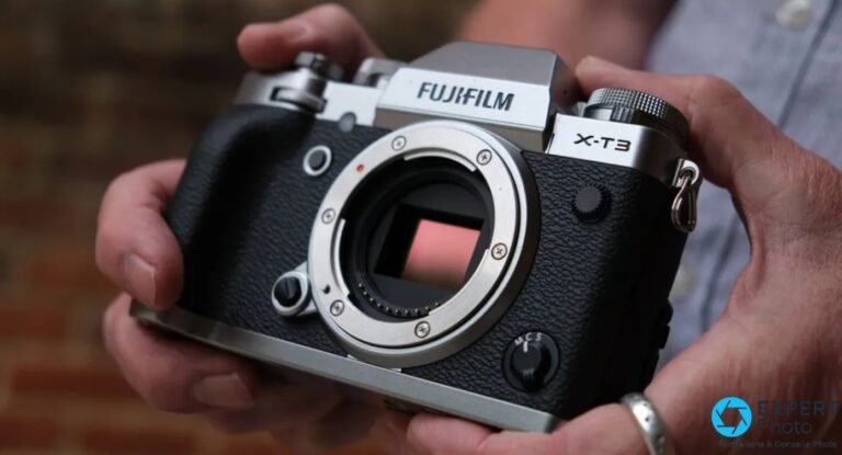 Fujifilm X-T3 silver boîtier nu tenu à deux mains, capteur APS-C visible dans la monture X, fond brique flou