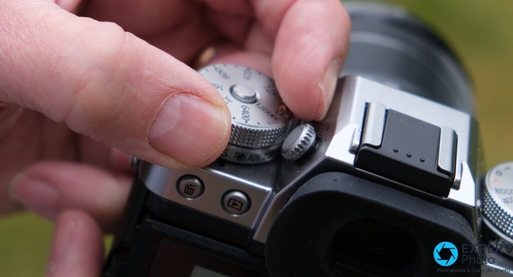 Gros plan sur la molette ISO du Fujifilm X-T3 manipulée par un doigt, déclencheur et bouton de lecture visibles