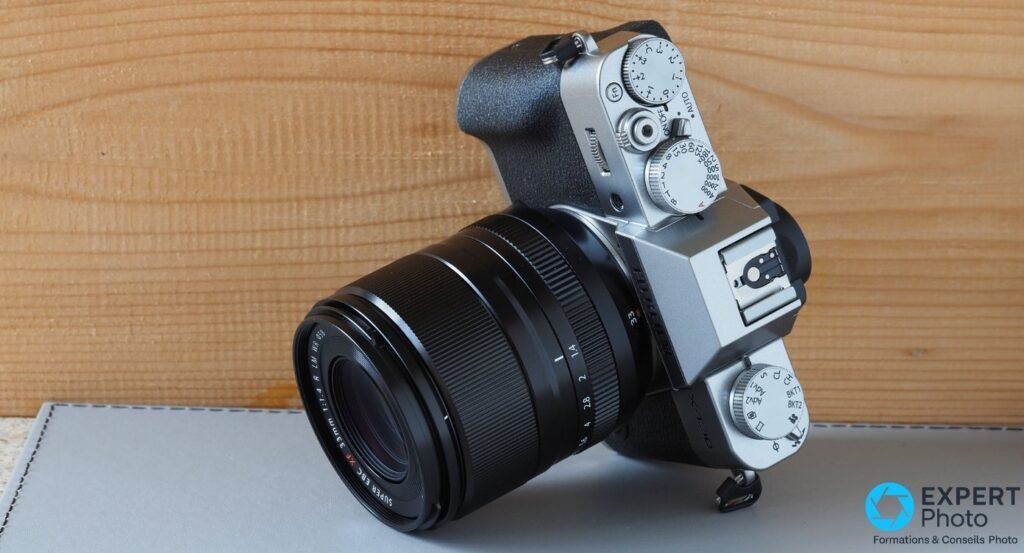 Fujifilm X-T30 II silver équipé d'un Fujinon XF 33mm f/1.4 R LM WR, vue 3/4 avant en plongée légère.