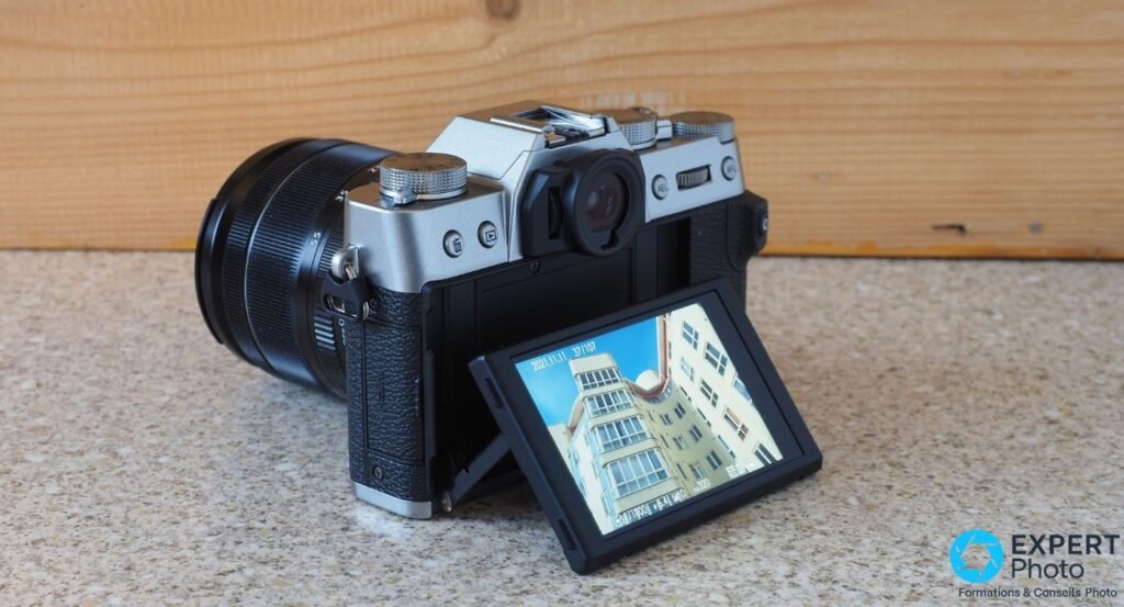 Fujifilm X-T30 II silver vu de l'arrière 3/4, écran tactile inclinable déployé vers le haut affichant un cliché.