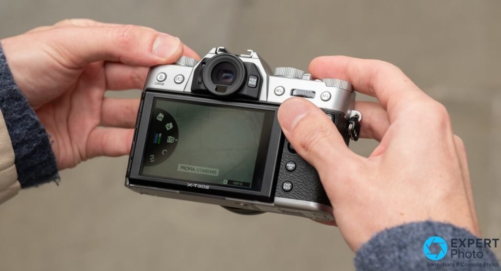 Vue arrière du Fujifilm X-T30 III silver, écran affichant le menu Film Simulation sur PROVIA/STANDARD, tenu en main.
