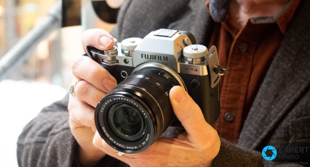 Fujifilm X-T4 silver tenu à deux mains avec objectif Fujinon XF 18-55 mm en mise en situation d'utilisation.