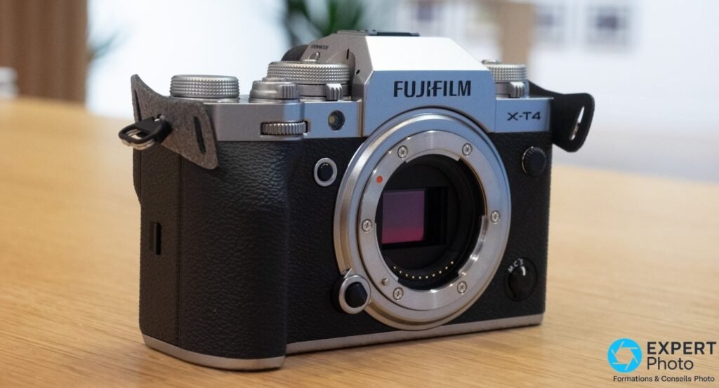 Boîtier Fujifilm X-T4 silver sans objectif, monture X et capteur APS-C visibles, posé sur table en bois clair.