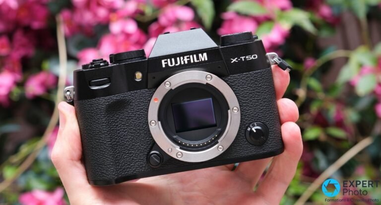 Fujifilm X-T50 boîtier nu tenu en main, monture X et capteur visibles, fond fleuri rose flou
