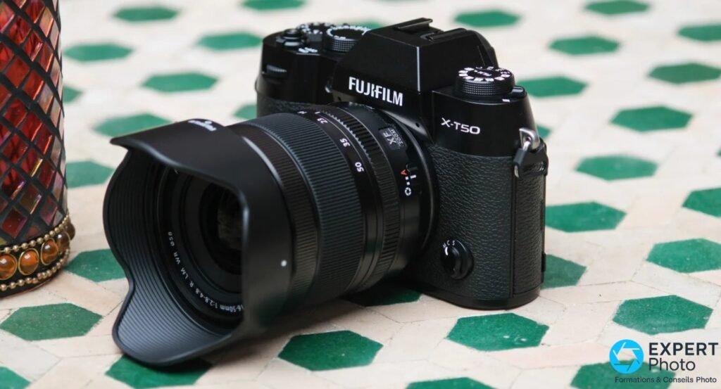 Boîtier Fujifilm X-T50 noir avec objectif XF 16-50mm et pare-soleil, vue de trois-quarts avant 