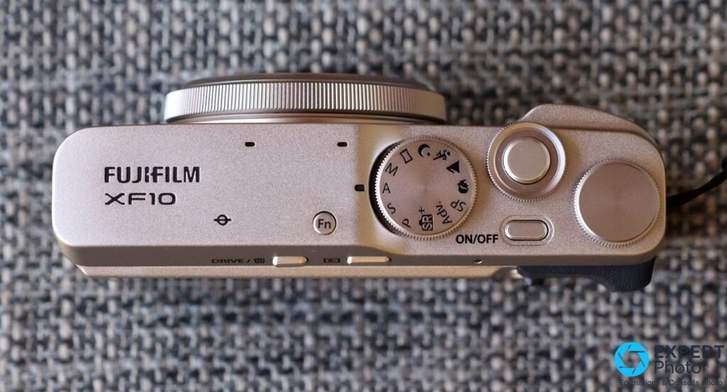 Capot supérieur du Fujifilm XF10 avec marquage FUJIFILM XF10, molette des modes M/A/S/P/SR+/Adv. et touche Fn 