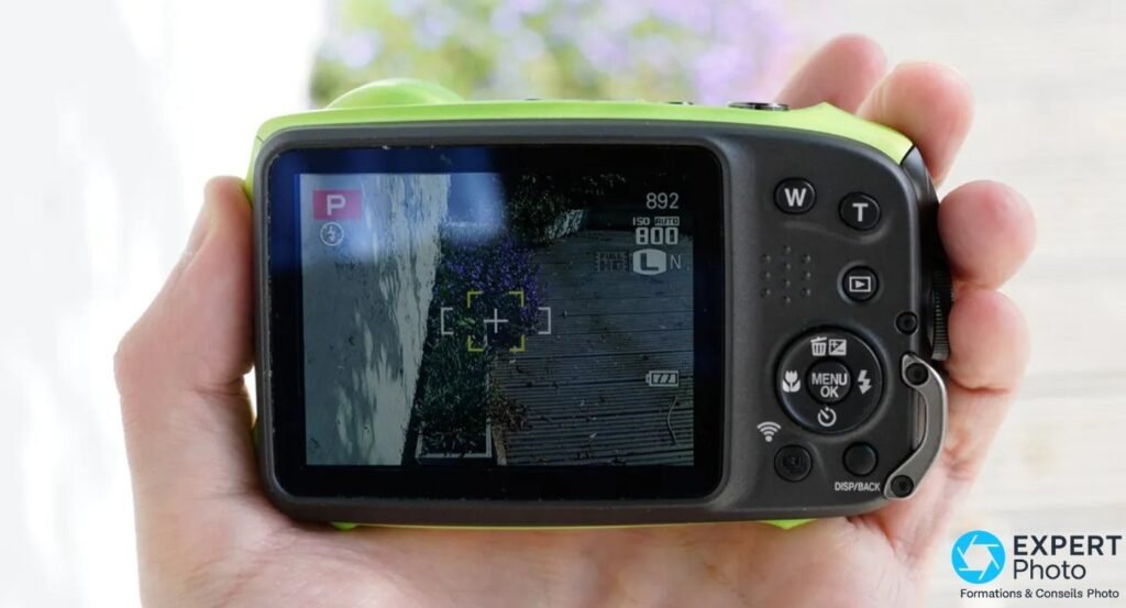 Fujifilm XP120 vue arrière en main, écran LCD en mode programme avec ISO 800 et Full HD affichés