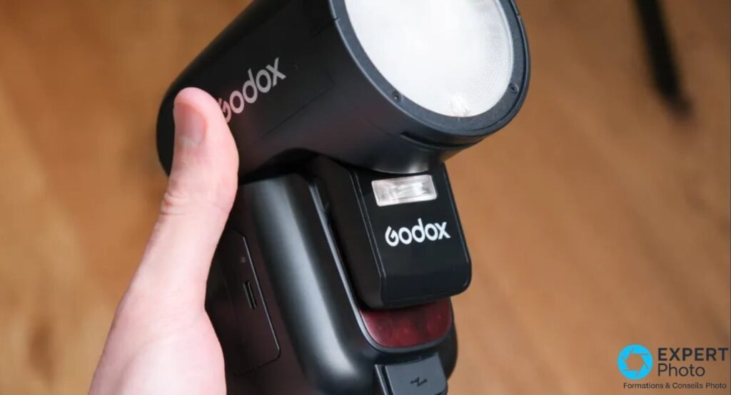 Godox V1 Pro en main, tete ronde et sub-flash SU-1 avec logos Godox, LED rouges visibles