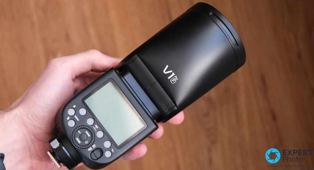 Godox V1 Pro tenu en main, vue arriere trois quarts, ecran et commandes, marquage V1 Pro F