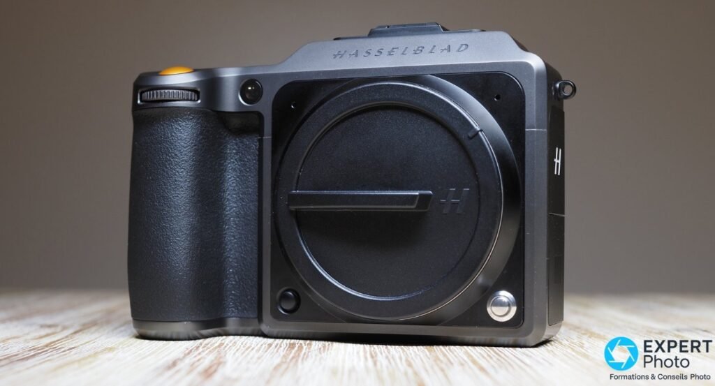 Boîtier moyen format Hasselblad système X de face, bouchon de boîtier à logo H, poignée noire et déclencheur orange