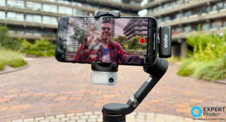 Hohem iSteady V3 de face, smartphone affichant un homme en train de filmer, émetteur Godox clipsé à droite
