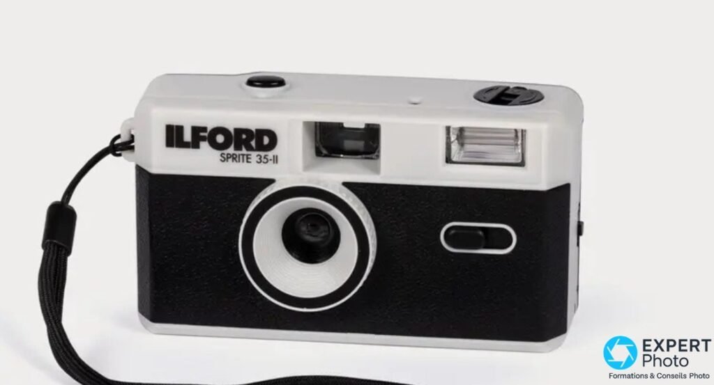 Ilford Sprite 35-II à capot argent et corps noir, objectif, flash et dragonne, sur fond clair de studio