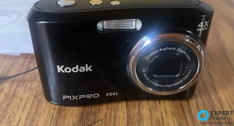 Compact Kodak PixPro FZ41 noir vu de face sur une table en bois, objectif zoom 4X WIDE et flash visibles.