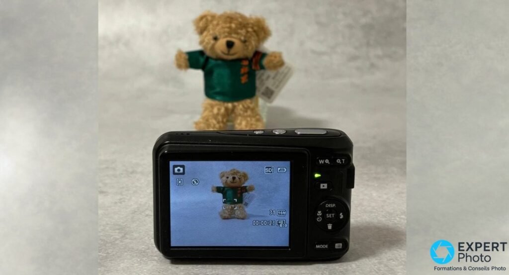 Dos du Kodak PIXPRO FZ43 noir, ecran LCD allume affichant un ourson, commandes et zoom W/T a droite