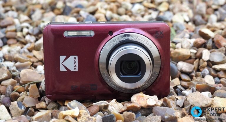 Compact Kodak Pixpro FZ55 rouge posé sur des graviers, objectif 5x déployé, logo Kodak et mention Full HD de face