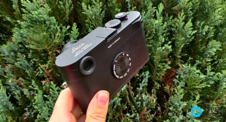 Vue plongeante sur le Leica M11-D tenu en main, capot supérieur, molette de vitesse et objectif Leica M monté.