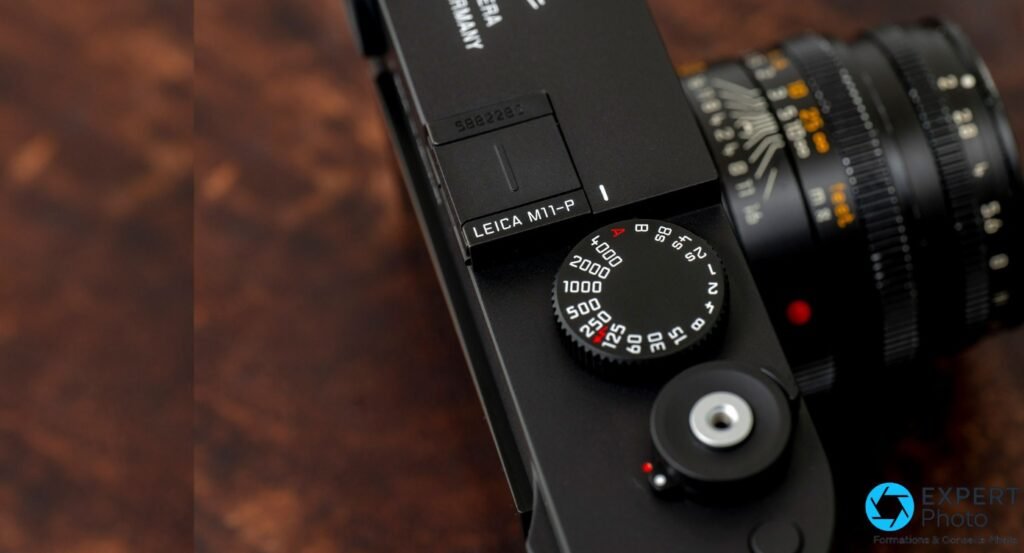Platine supérieure du Leica M11-P noir avec gravure du modèle, molette de vitesses et point rouge, vue en plongée