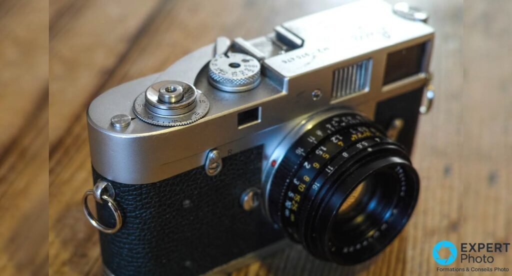 Boîtier Leica M2 chromé vu de trois quarts en plongée, sélecteur de vitesses 1 à 1000 et molette d'armement visibles. 