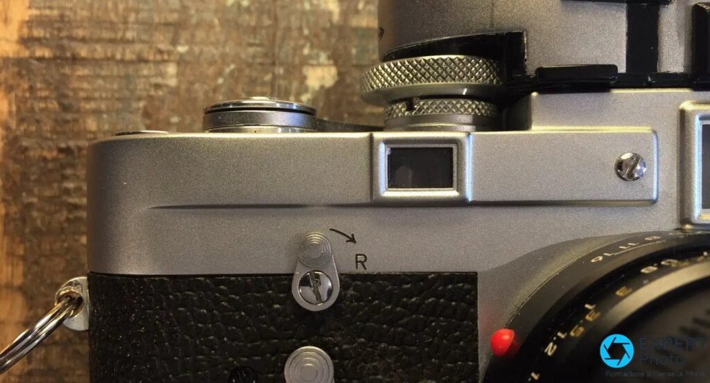 Capot superieur d'un Leica M3 : fenetre rectangulaire des cadres, selecteur R et vis chromee, gainage cuir noir. 