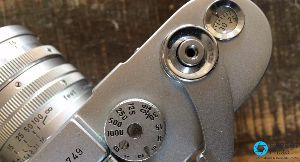 Gros plan d'un Leica M3 : molette des vitesses gravee 1000 a B, declencheur et compteur de vues affichant 30.