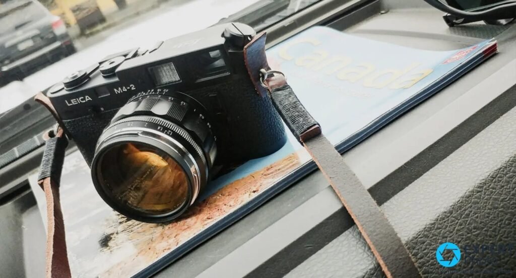  Leica M4-2 noir avec objectif posé sur un magazine de voyage à couverture Canada, sur un tableau de bord.