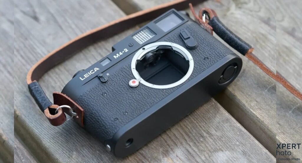 Leica M4-2 noir vu de trois quarts avant, monture M ouverte sans objectif, point rouge d'alignement et levier R visibles.