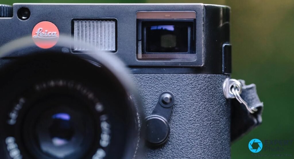 Gros plan du haut d'un Leica M8 : pastille rouge Leica, fenêtre de cadrage et viseur télémétrique, attache de dragonne.