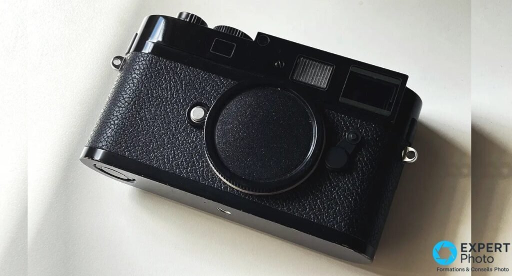 Boitier telemetrique Leica M noir avec capuchon de boitier, vu de face trois-quarts sur fond clair, modele non confirme