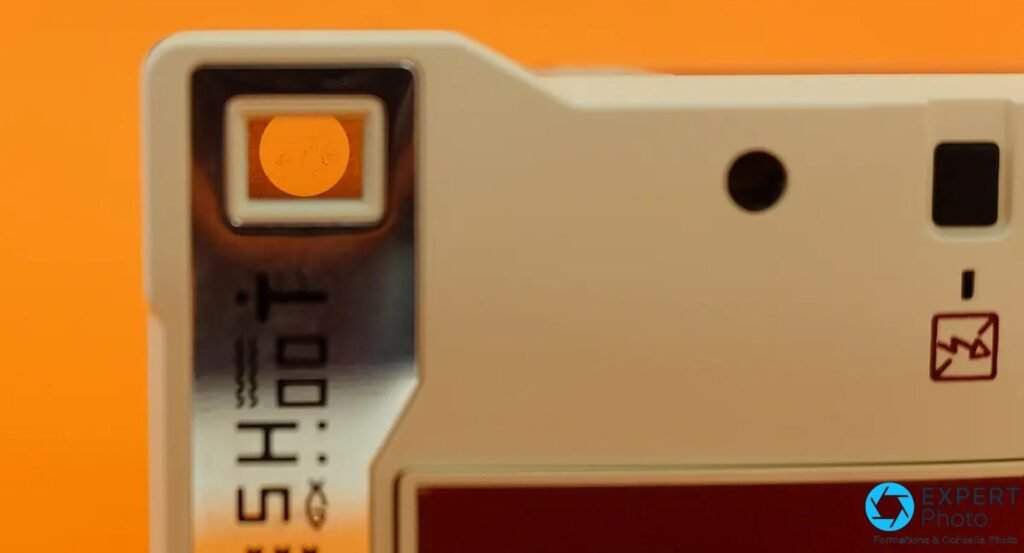 Lomo'Instant Automat, détail du dessus avec molette gravée SHOOT et petite fenêtre, fond orange