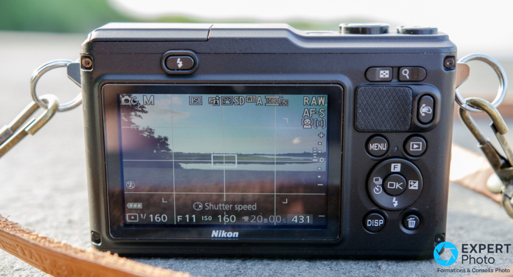 Nikon 1 AW1 vu de dos, écran LCD en visée live view, commandes arrière visibles, courroie cuir camel