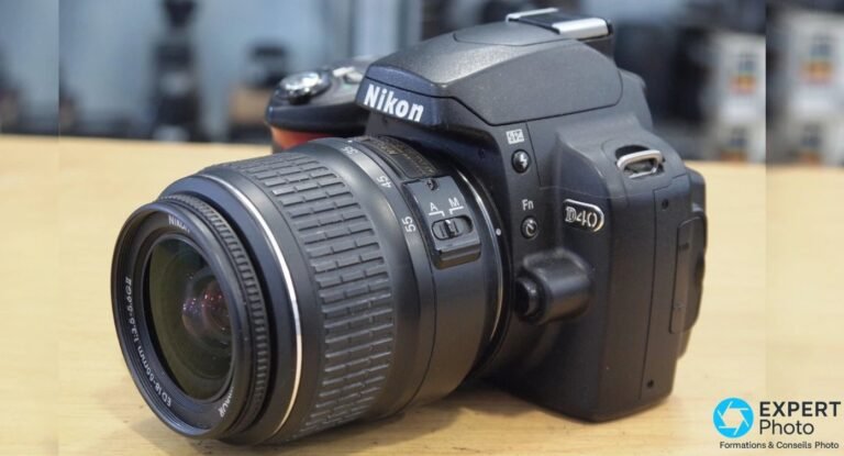 Nikon D40 en trois-quarts avant droite, marquage « D40 » gravé visible, bouton Fn et commutateur A/M sur l'objectif 18-55.