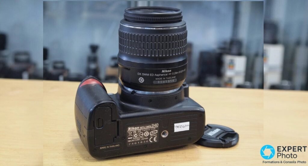 Nikon D40 vu de dessous avec étiquette « Nikon DIGITAL CAMERA D40 », numéro de série et étiquette de revendeur d'occasion. 