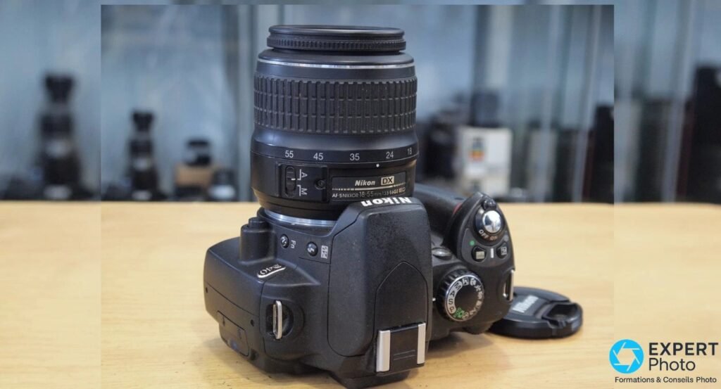 Nikon D40 vu de dessus, molette de modes P/S/A/M et programmes scènes, objectif AF-S DX 18-55mm extended.