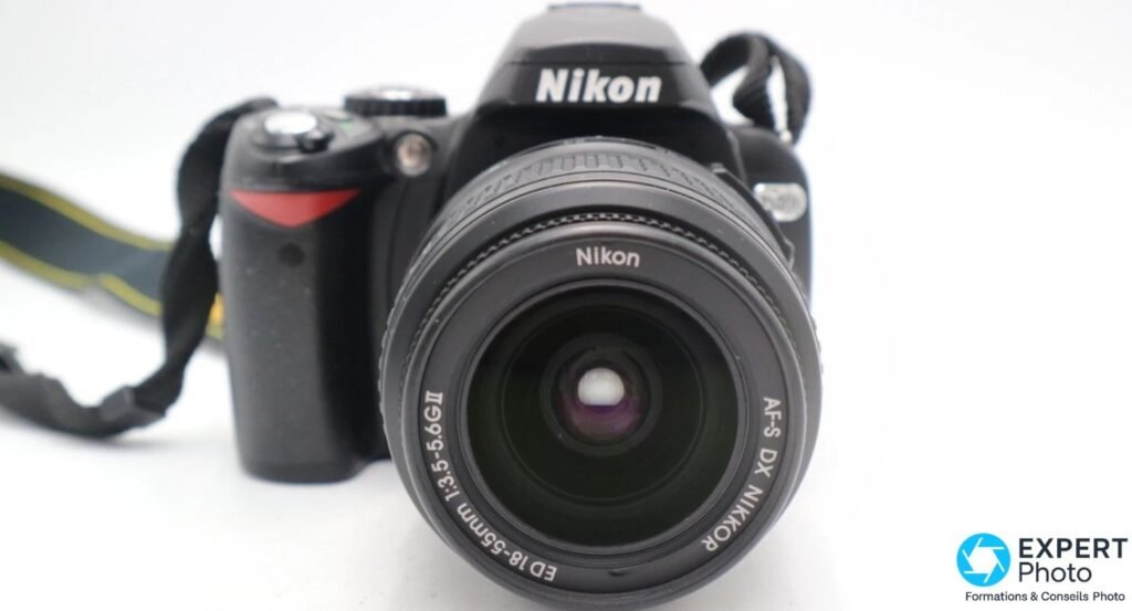 Vue frontale du Nikon D40X avec son objectif kit AF-S DX NIKKOR ED 18-55mm 1:3.5-5.6G II, lentille visible.
