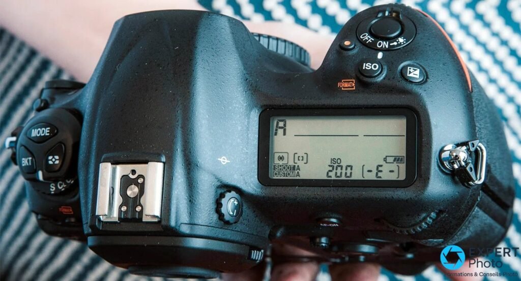 Vue du dessus du Nikon D5 avec écran LCD supérieur, sélecteur MODE/BKT, bouton ISO et sabot flash.